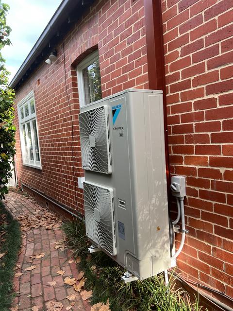 Wall-mounted Daikin unit on a heritage brick home